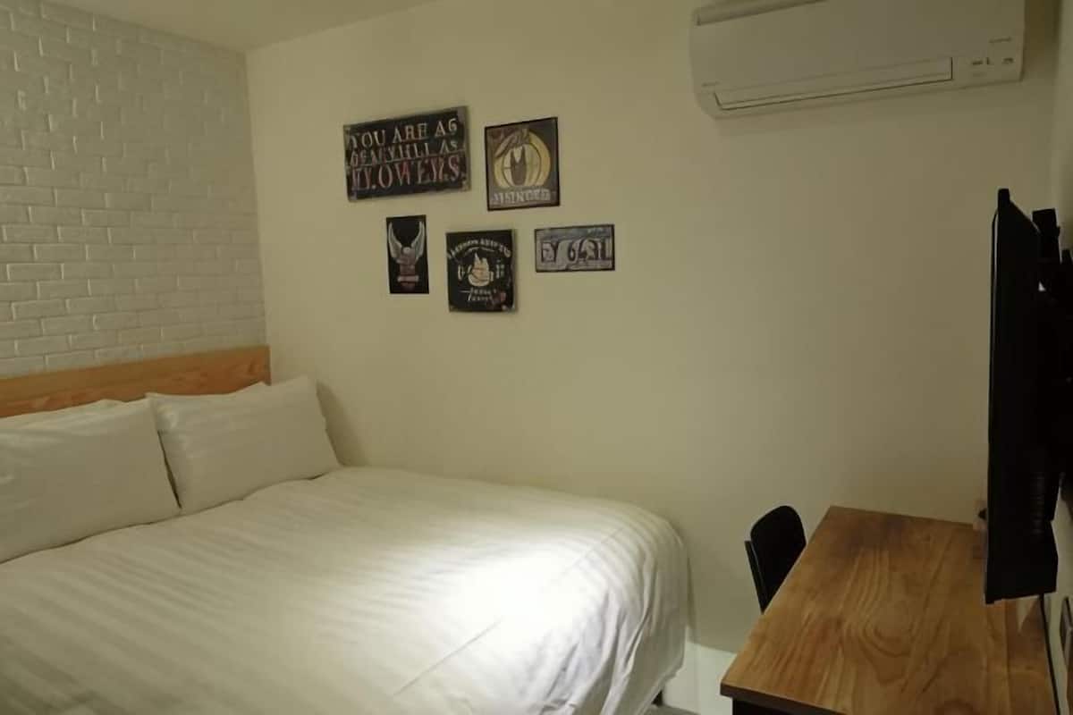 A bedroom with a bed, a wooden desk, and four wall-mounted signs.
