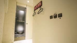 Um corredor com uma porta que dá para um quarto, uma placa na parede com a palavra “LIVE” e três interruptores de parede pequenos.