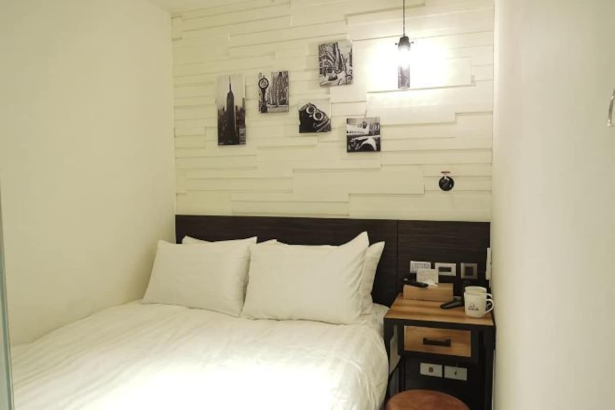 A neatly arranged bedroom with a bed, bedside table, and wall-mounted artwork.