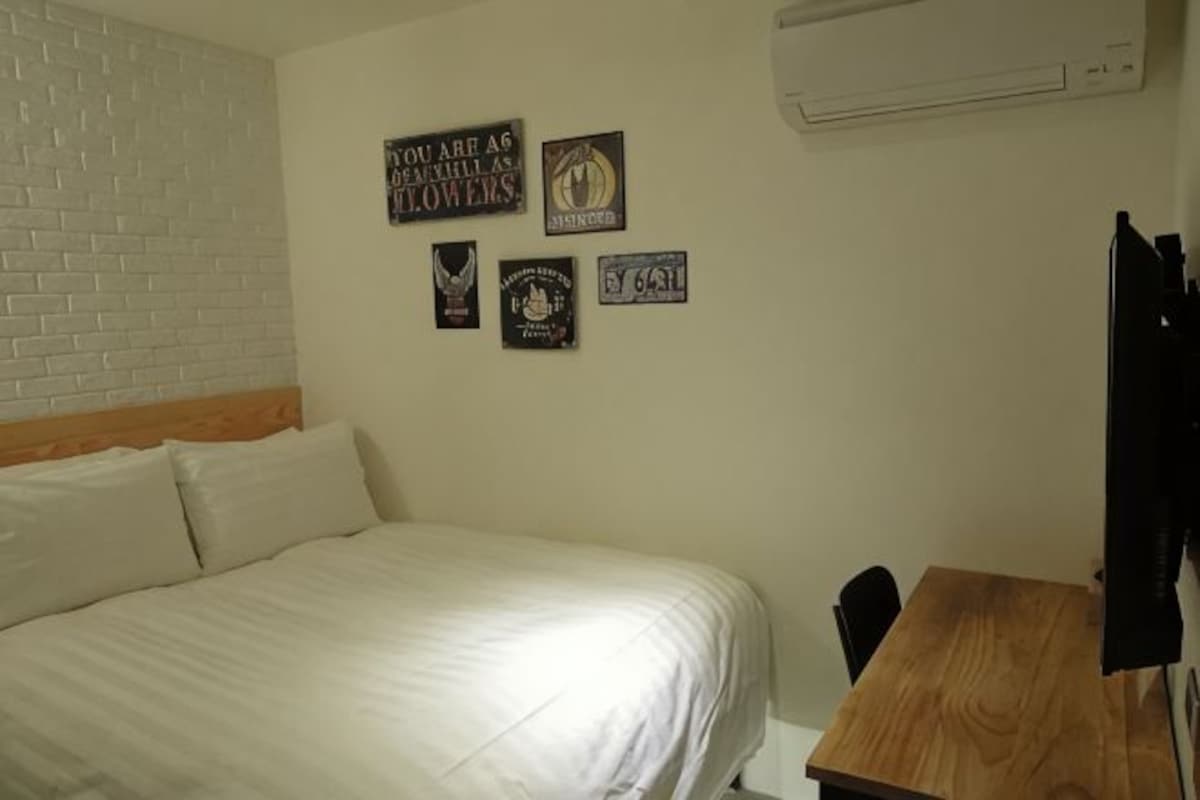 A bedroom with a bed, a wooden desk, and four wall-mounted signs.