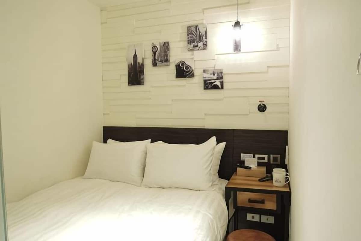 A neatly arranged bedroom with a bed, bedside table, and wall-mounted artwork.