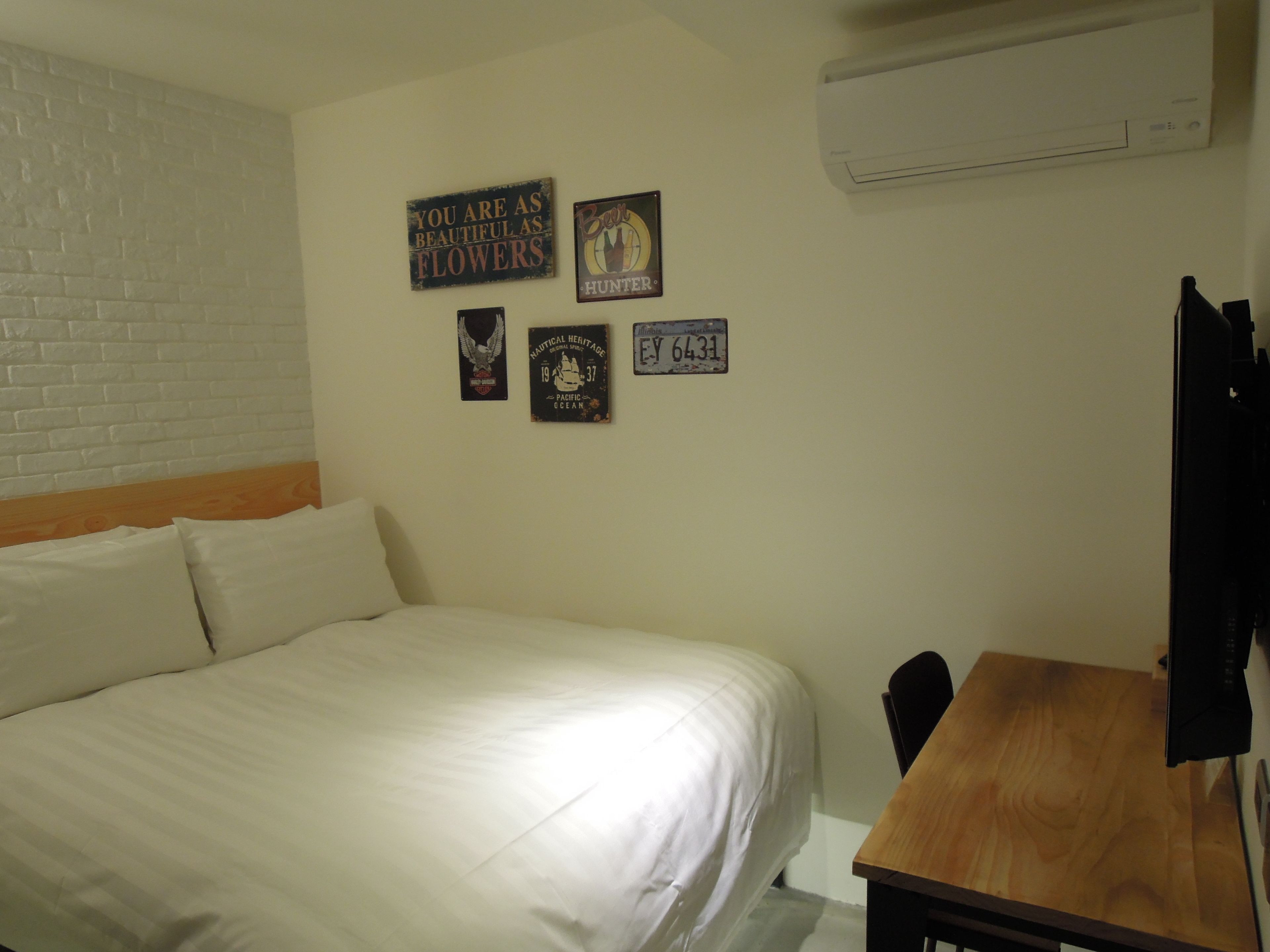 A bedroom with a bed, a wooden table, and four wall-mounted signs.