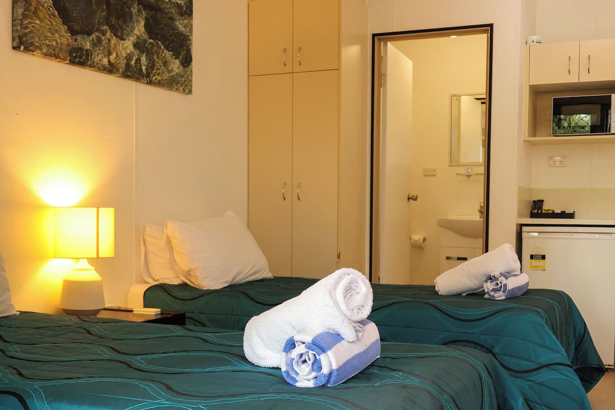 Une chambre d’hôtel avec deux lits, un ventilateur de plafond, une télévision et un four à micro-ondes.
