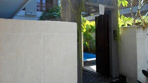 Eine Betonwand mit einer kleinen Öffnung, die zu einem Poolbereich führt.