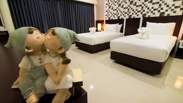 Quarto de hotel com duas camas, cabeceira xadrez e uma estátua decorativa de duas figuras sobre uma mesa.