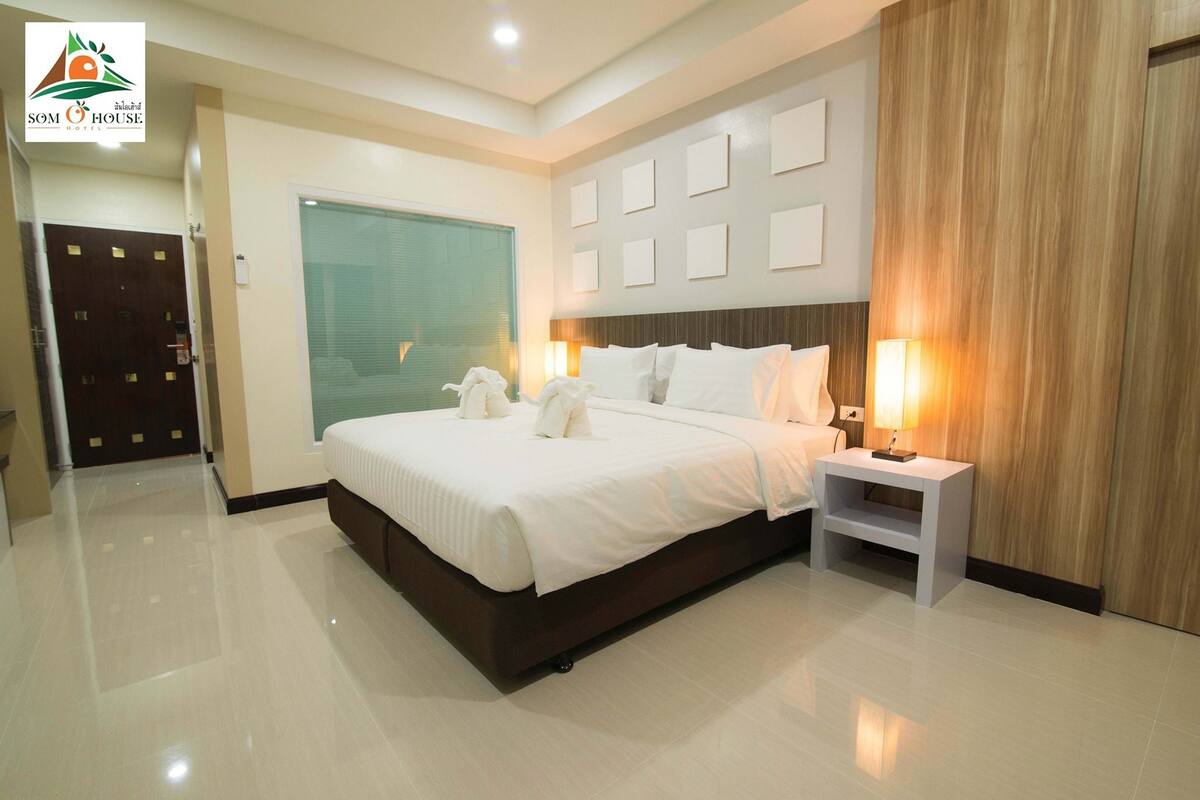 A modern hotel bedroom with a large bed, bedside tables, and a wooden accent wall.