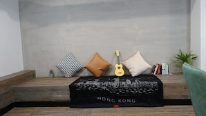 A room with a bed, a guitar, and a cushion with 'HONG KONG' printed on it. - Homy Inn North Point (Hong Kong)