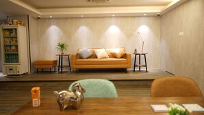A modern living room with a sofa, a small table, a lamp, and a refrigerator. - Homy Inn North Point (Hong Kong)