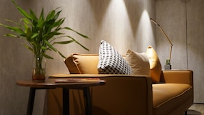 A modern living room with a sofa, a small table, a potted plant, and a floor lamp. - Homy Inn North Point (Hong Kong)