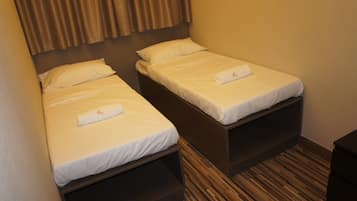 Two single beds with white linens and towels, wooden headboards, and a striped carpet.