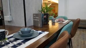 A dining area with a wooden table, a book titled "The Victoria Harbour", and a potted plant. - Homy Inn North Point (Hong Kong)