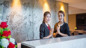 A reception area with a marble wall and a reception desk. - Kesornboutique Hotel (Buriram)