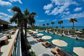 A poolside area with lounge chairs and umbrellas, palm trees, and a view of the ocean. - The Uza Terrace Beach Club Villas (Yomitan)