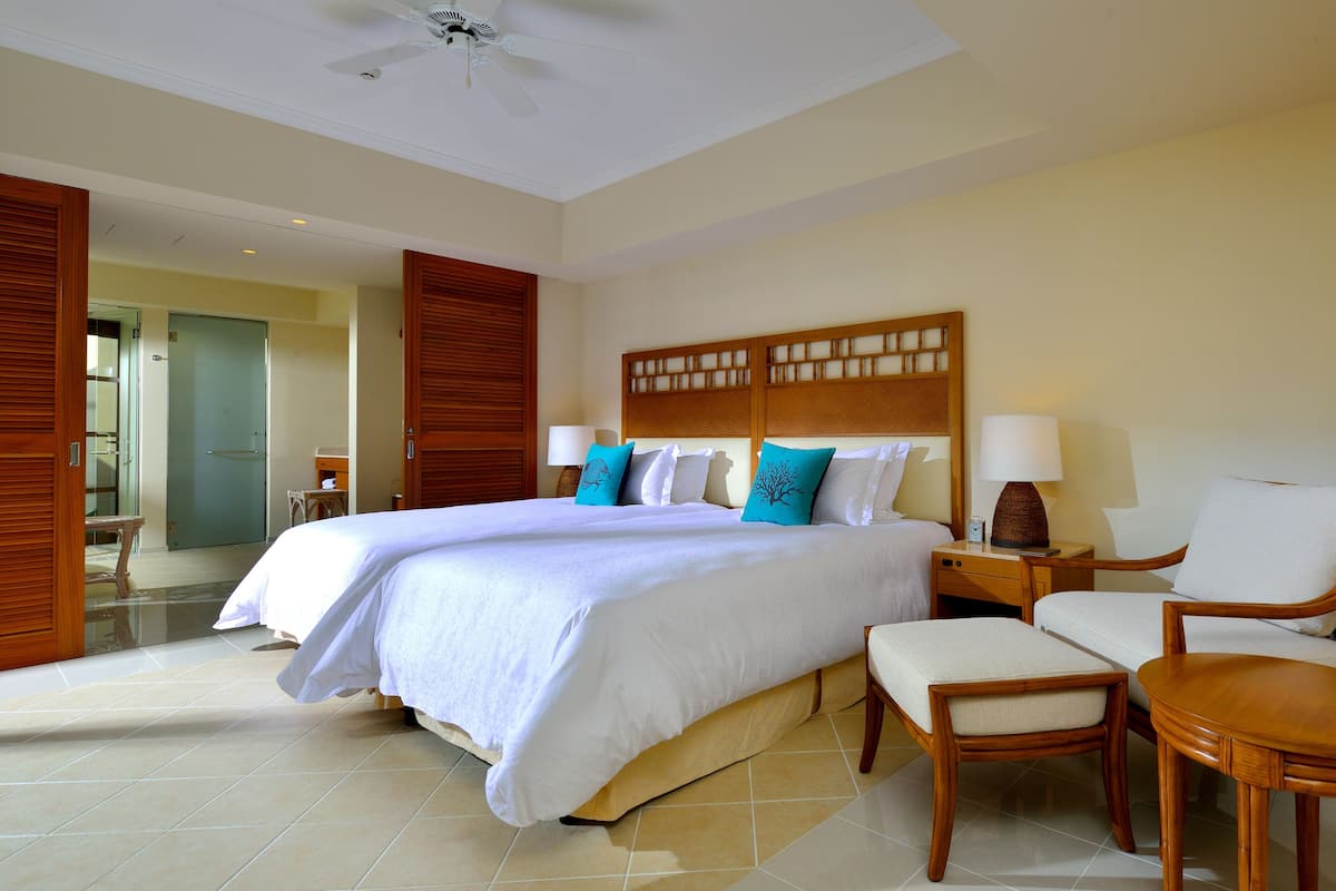 A hotel room with a large bed, a wooden headboard, a chair, a nightstand, and a lamp.