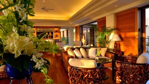 A spacious lobby with a high ceiling, a seating area with a sofa and chairs, a coffee table, and a decorative plant. - The Uza Terrace Beach Club Villas (Yomitan)