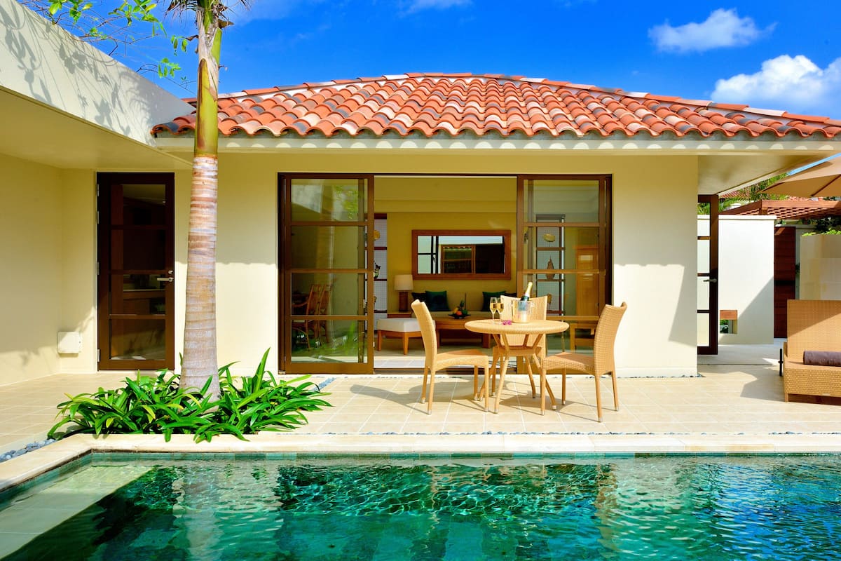 A poolside area with a dining set, chairs, and a table.