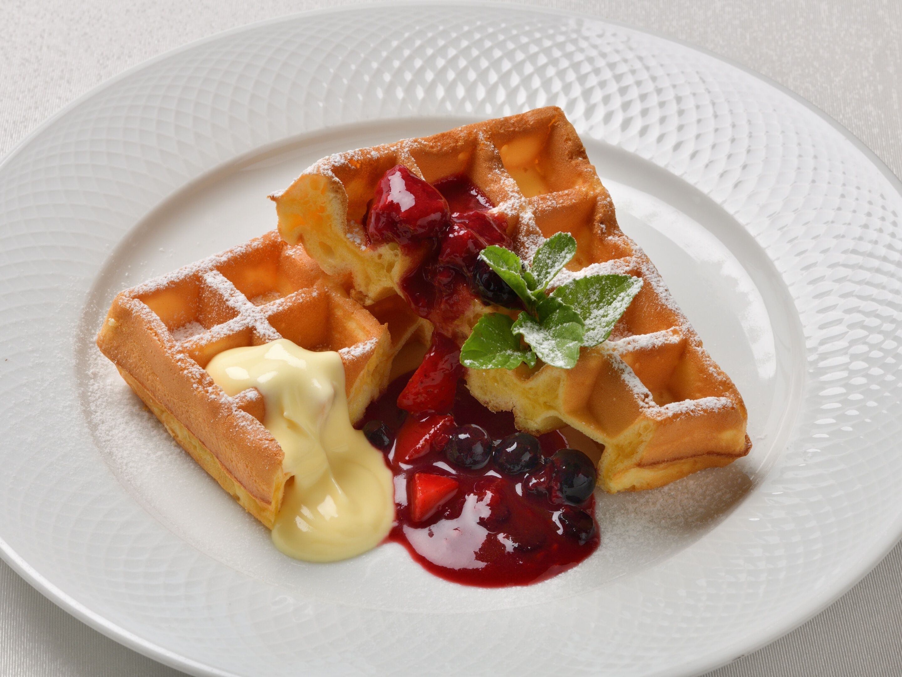 A waffle with berries and whipped cream on a plate.