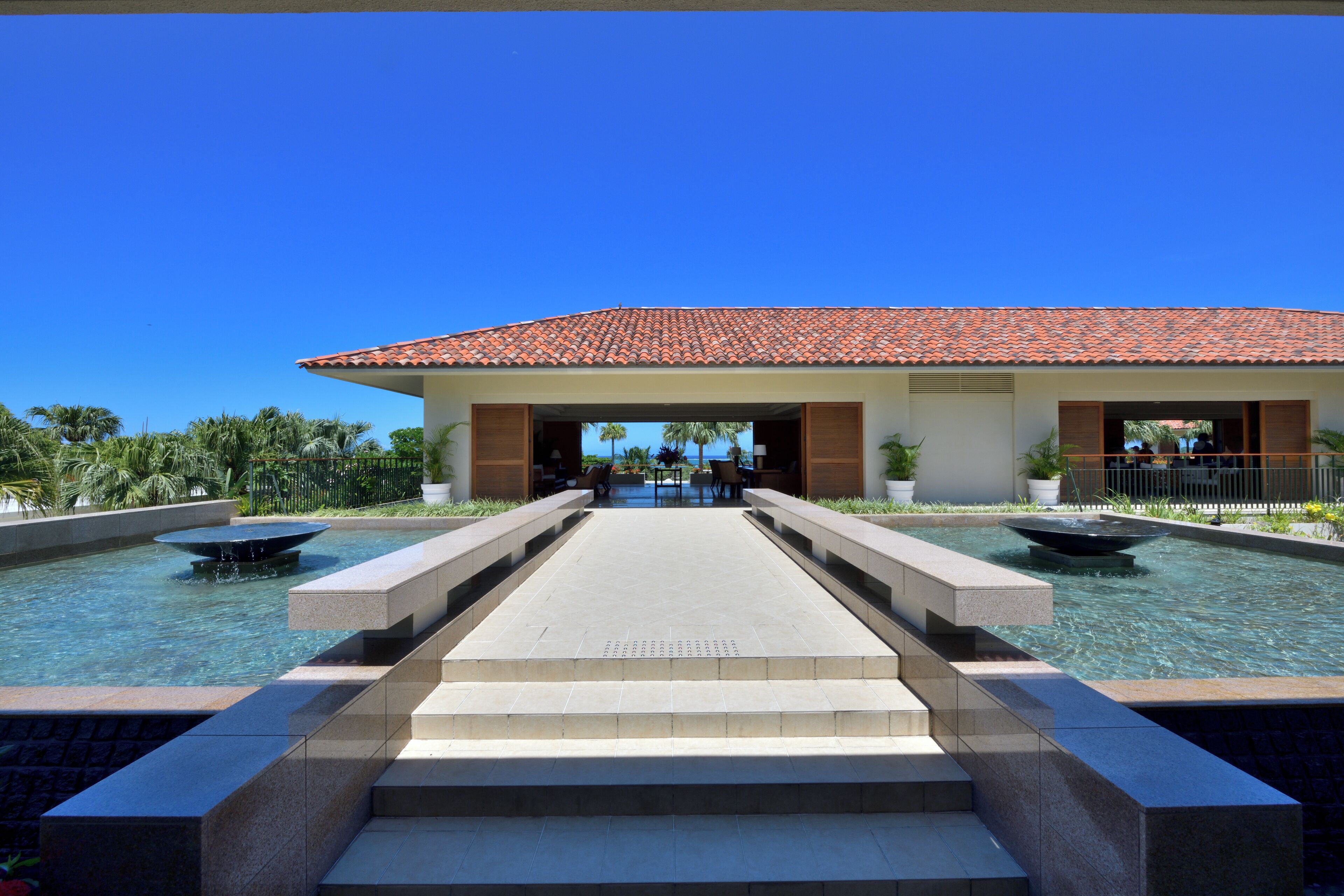 A hotel with a tiled roof, a central courtyard with a fountain, and a pool.