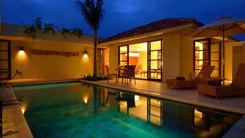 A swimming pool with lounge chairs and a dining area.