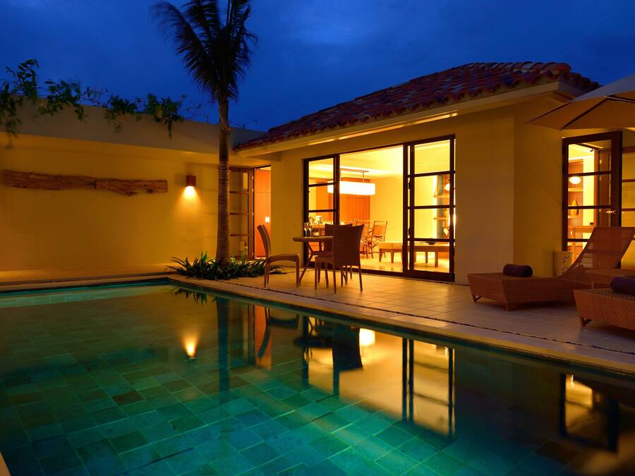 A swimming pool with lounge chairs and a dining area.