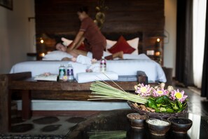 Un cuarto de spa con una cama, camilla de masaje y una mesa con un arreglo floral y varias botellas.