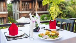 A dining table with a plate of food, a glass of water, and red napkins. - JAVA WOODEN VILLA (Siem Reap)
