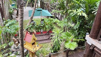 Una terraza de madera con un pequeño santuario y abundante vegetación tropical.