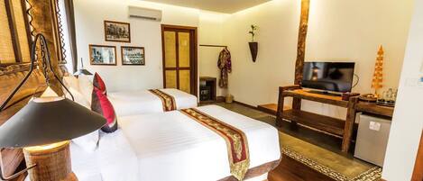 A hotel room with a large bed, a television, a desk, and a small refrigerator.