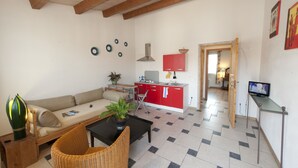 A living room with a sofa, a coffee table, a wicker chair, and a television on a stand. - Agriturismo La Gironda (Forlì)