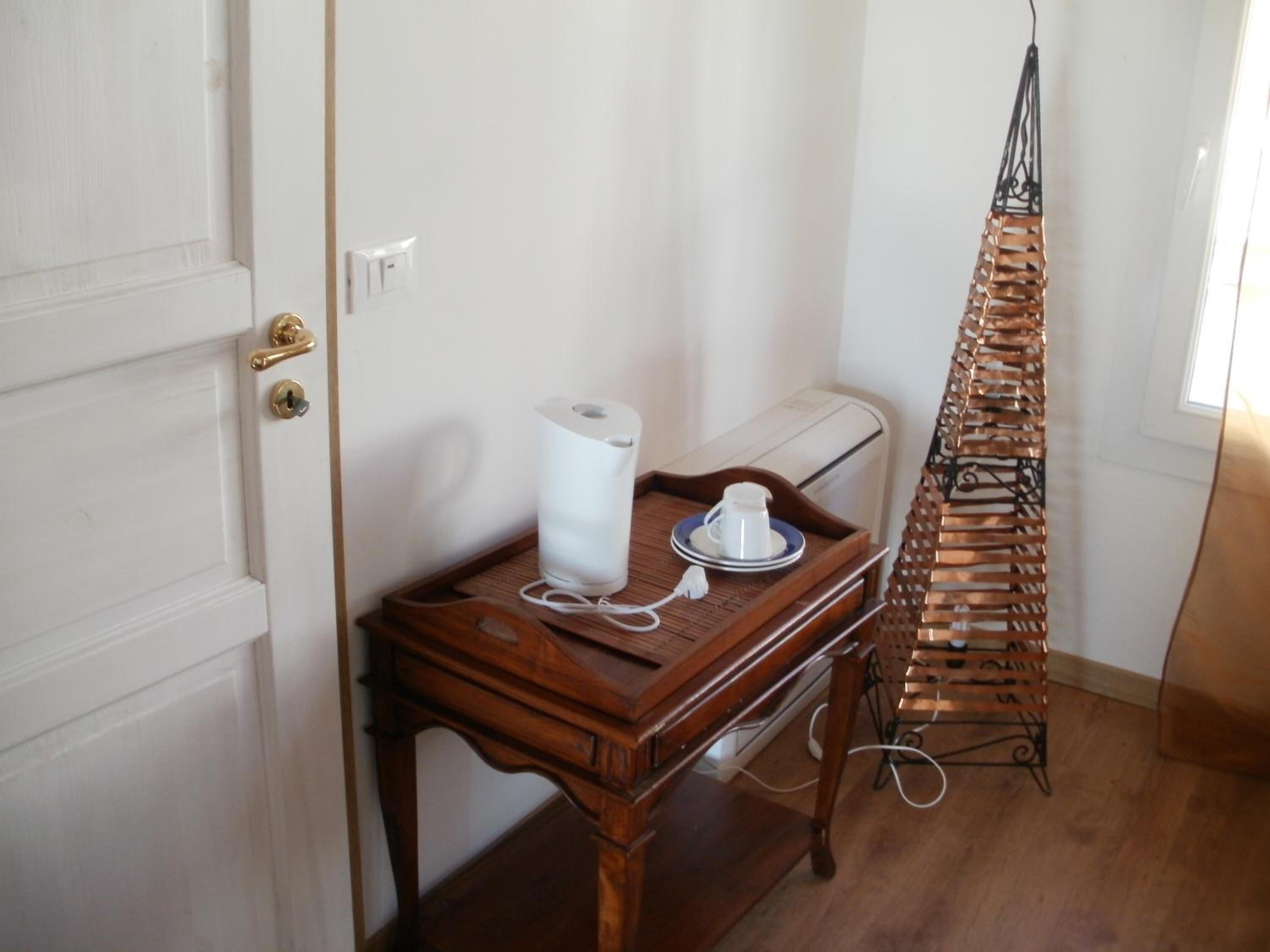 Une petite table en bois, sur laquelle se trouvent une tasse et une soucoupe blanches, un rouleau de papier toilette et un plateau.
