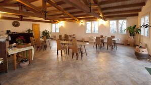 A spacious dining area with wooden beams, wicker chairs, and a large table. - Agriturismo La Gironda (Forlì)