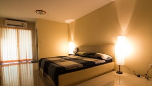 A bedroom with a bed, a bedside lamp, and an air conditioning unit. - Dae Ma Place (Nonthaburi)