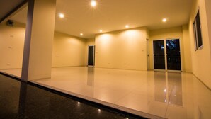 A spacious, well-lit indoor area with a polished floor, a door, and a window with a view of the outside. - Dae Ma Place (Nonthaburi)