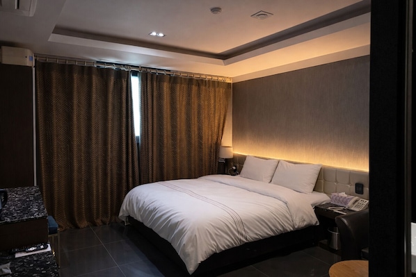A modern hotel room with a large bed, a bedside table, a lamp, and a curtain. - Zenith Hotel (Bucheon)