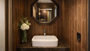 A bathroom with a rectangular sink, a mirror, and a vase with flowers. - Zenith Hotel (Bucheon)