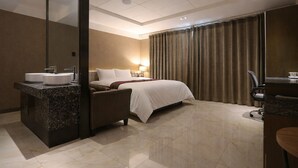 A modern hotel room with a bed, a desk, a mirror, and a bathroom with two sinks. - Zenith Hotel (Bucheon)