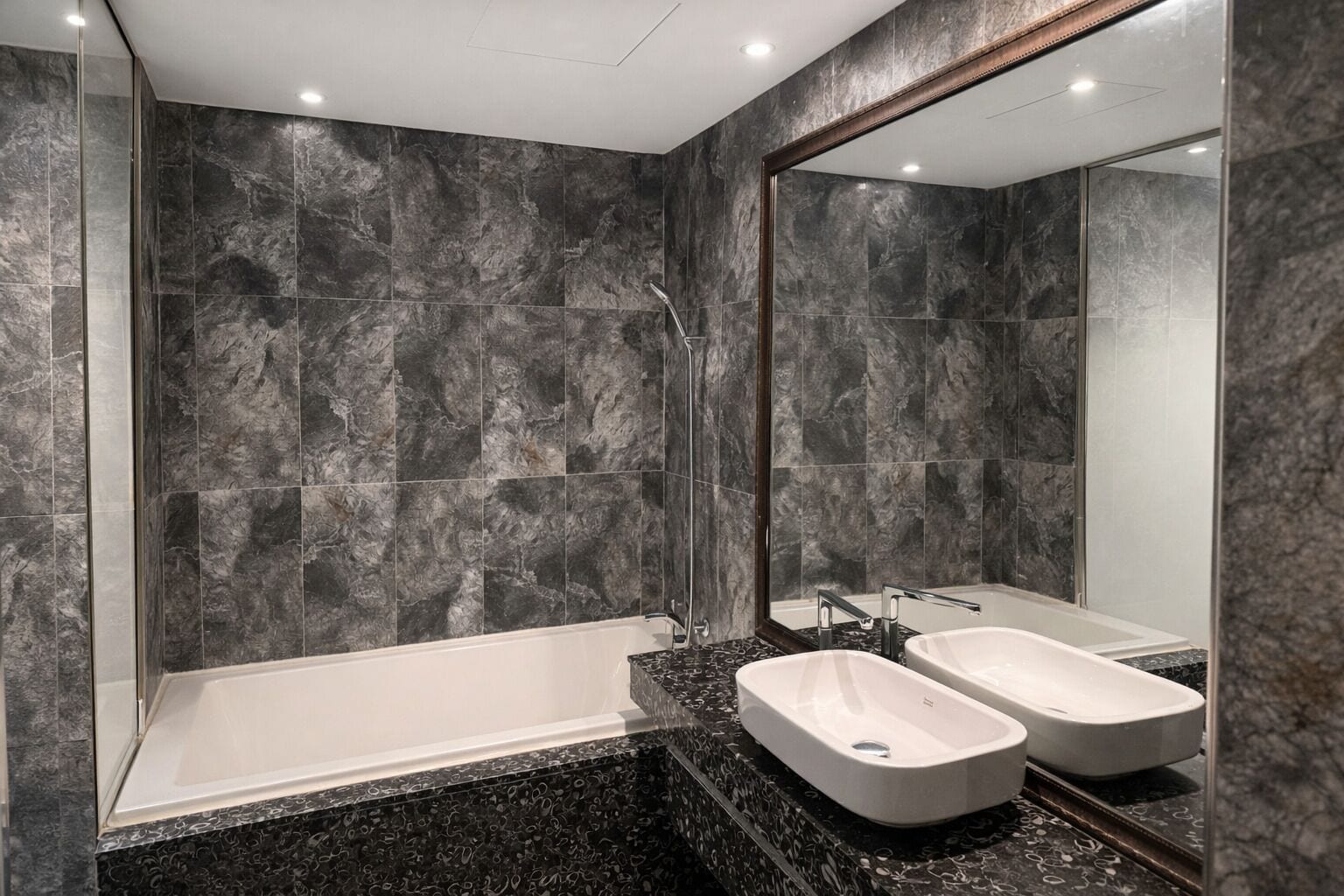 A modern bathroom with a bathtub, two sinks, and a large mirror.