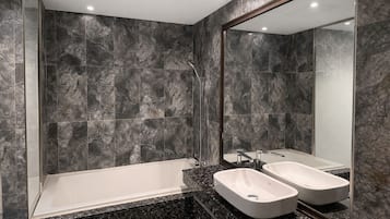 A modern bathroom with a bathtub, two sinks, and a large mirror.