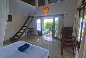 A room with a bed, a chair, a staircase, and a view of the sea. - Wawa Wewe Rock (Karangasem)