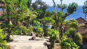 A tropical garden with a pool, palm trees, and a view of the sea. - Wawa Wewe Rock (Karangasem)