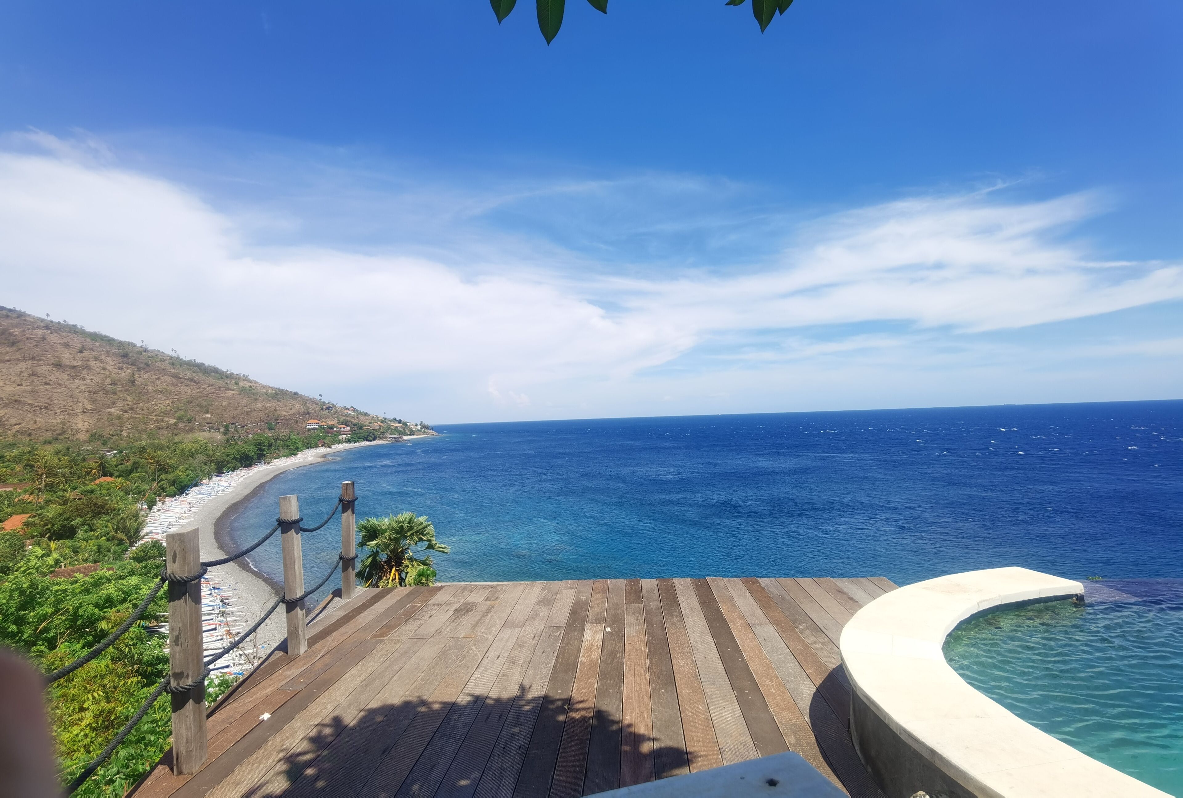 Una terraza de madera con vista a una playa y una vista despejada del océano y la costa distante.
