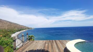 Una terraza de madera con vista a una playa y una vista despejada del océano y la costa distante.