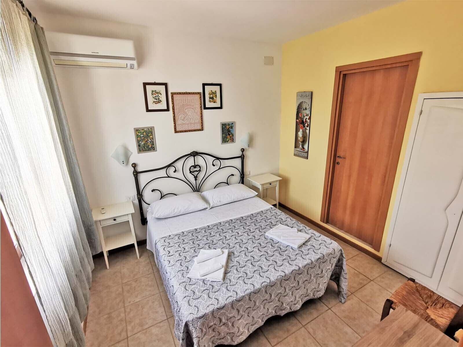 A neatly arranged bedroom with a bed, bedside tables, a wardrobe, and wall art.