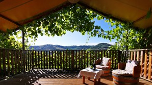 A wooden deck with a table and two chairs under a pergola with vines. - Il Girasole (Massignano)