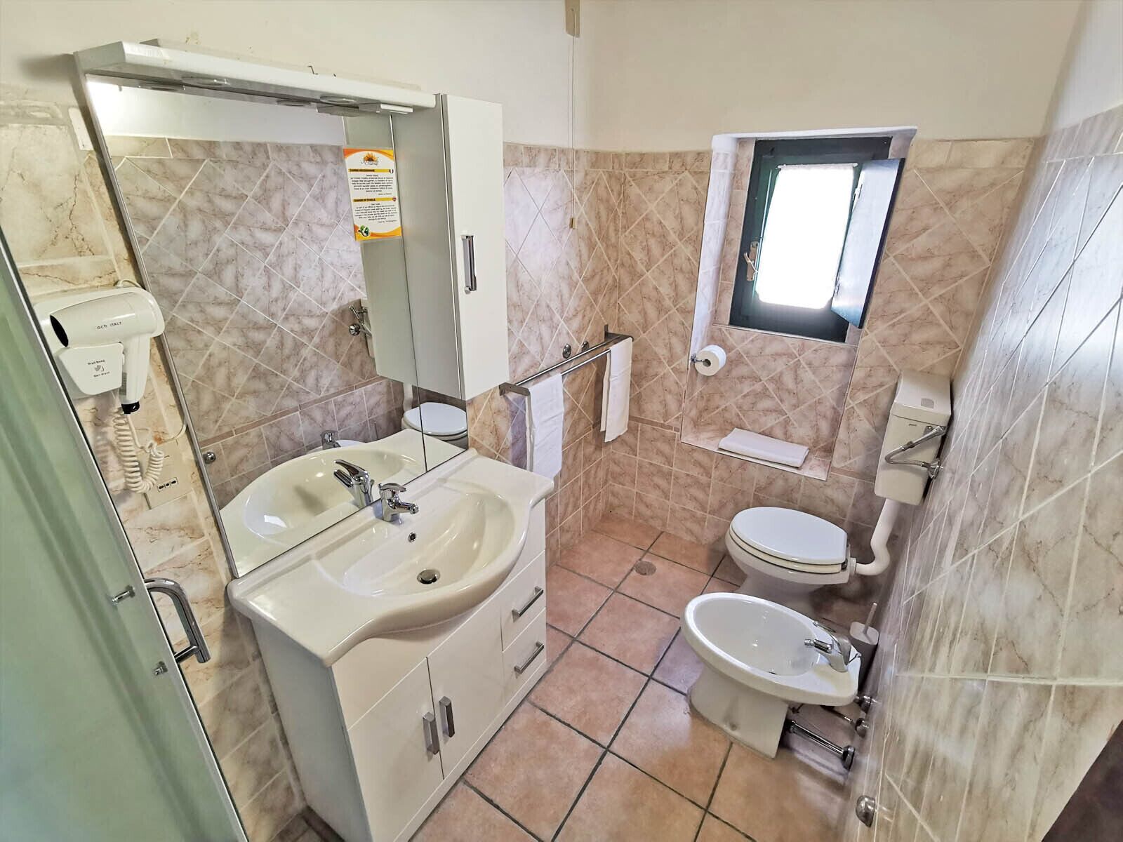 Un baño con lavamanos, espejo, inodoro y bidé.