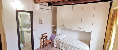 A bedroom with a wooden ceiling, a bed, a chair, and a wardrobe.