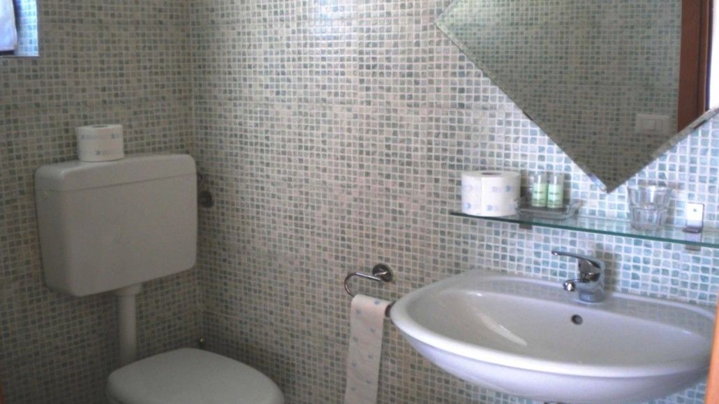 Un baño con inodoro, lavamanos y espejo.