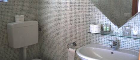 Un baño con inodoro, lavamanos y espejo.