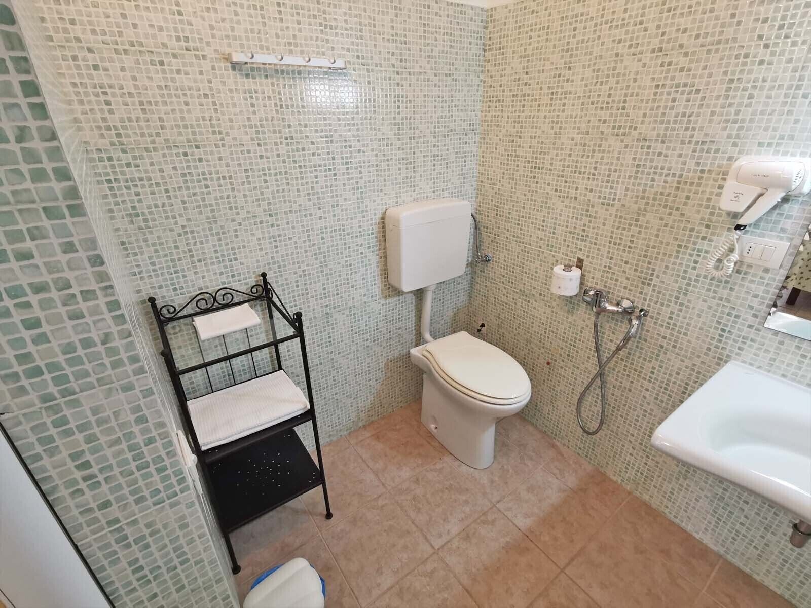Uma casa de banho com sanita, lavatório e chuveiro.