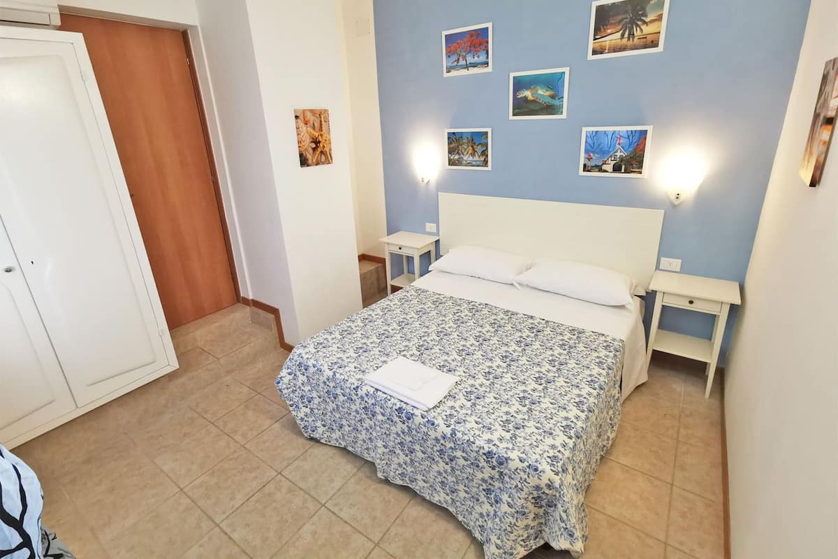 A bedroom with a bed, nightstands, and wall art.